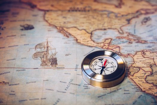 Old vintage retro golden compass on ancient map. Selective focus, shallow depth of field. Concept of world travel, sightseeing and tourism.