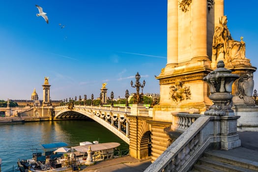 Pont Alexandre III bridge over river Seine in the sunny summer morning. Bridge decorated with ornate Art Nouveau lamps and sculptures. The Alexander III Bridge across Seine river in Paris, France.