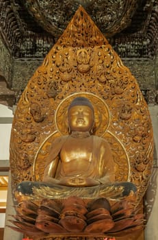 Kaneohe, Oahu, Hawaii, USA. - January 11, 2020: Closeup of golden Buddha in lotus position statue in Byodo-In Buddhist temple with backdrop and baldachin.