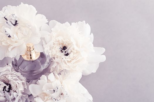 Violet fragrance bottle as luxury perfume product on background of peony flowers, parfum ad and beauty branding design