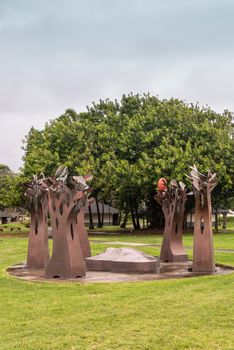 Kahului, Maui,, Hawaii, USA. - January 12, 2020: Portrait of Brown rusty metal group of trees statue on green lawn at University of Hawaii, Maui college campus. Gray cloudy sky. Green foliage in back.