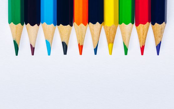 Color pencils isolated on white background. Close up of colored rainbow pencils for drawing, concept of preparing for school and discounts on stationery before the school year.