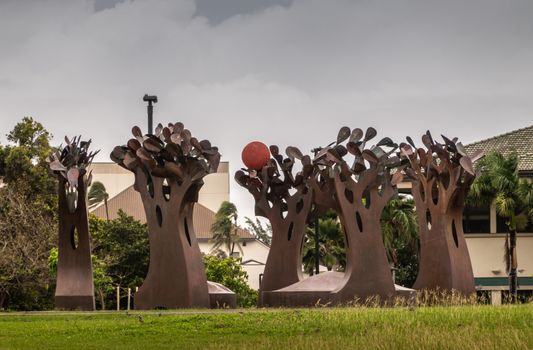 Kahului, Maui,, Hawaii, USA. - January 12, 2020: Brown rusty metal group of trees statue on green lawn at University of Hawaii, Maui college campus. Gray cloudy sky.