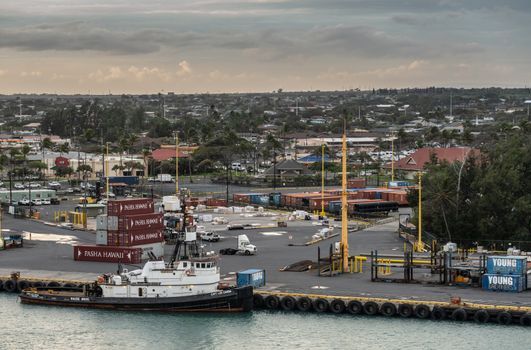 Kahului, Maui,, Hawaii, USA. - January 13, 2020: Sause Bros tugboat docked at container. yard under evening cloudscape. Cityscape in back. Yellow light poles and shipping containers in different colors up front.