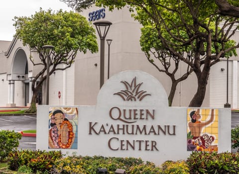 Kahului, Maui,, Hawaii, USA. - January 12, 2020: Colorful sign at entrance to Queen Kaahumanu shopping center, set in colorful plantings and backed with green foliage in front of light beige walls.