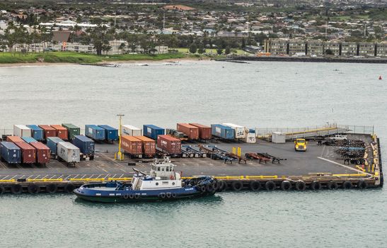 Kahului, Maui,, Hawaii, USA. - January 13, 2020: Kalamag, a young bros tugboat docked at pier with shipping containers on trailers. Cityscape in back.