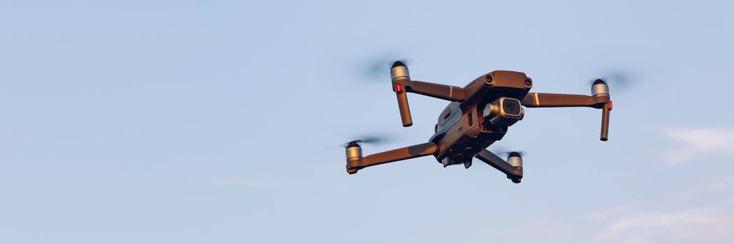 Drone flying over landscape. UAV drone copter flying with digital camera. Drone flying overhead in cloudy blue sky. Quad copter is flying over the  field.