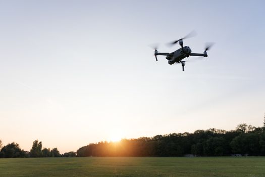 Drone flying over landscape. UAV drone copter flying with digital camera. Drone flying overhead in cloudy blue sky. Quad copter is flying over the  field.