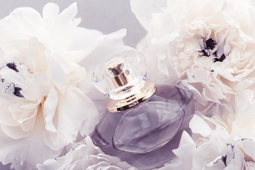 Violet fragrance bottle as luxury perfume product on background of peony flowers, parfum ad and beauty branding design