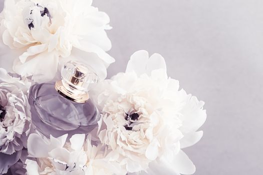 Violet fragrance bottle as luxury perfume product on background of peony flowers, parfum ad and beauty branding design