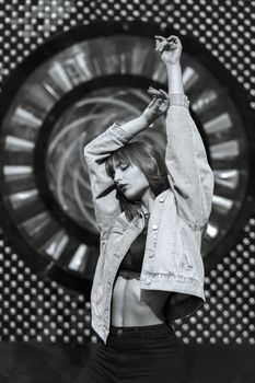 Fashionable young woman wears lace bra and blue denim jacket posing at the city building. Monochrome color