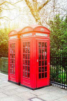 Red telephone box in street with historical architecture in London.