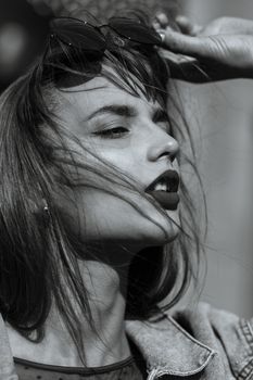 Closeup portrait of magnificent young woman with red lips wears jeans jacket. Monochrome color