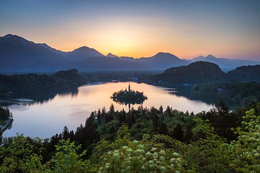 Dramatic sunrise on lake Bled, sunrise view on Bled lake, island, Pilgrimage Church of the Assumption of Maria and Castle with mountain range (Stol, Vrtaca, Begunjscica). Bled, Slovenia,