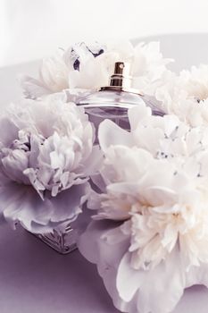 Violet fragrance bottle as luxury perfume product on background of peony flowers, parfum ad and beauty branding design