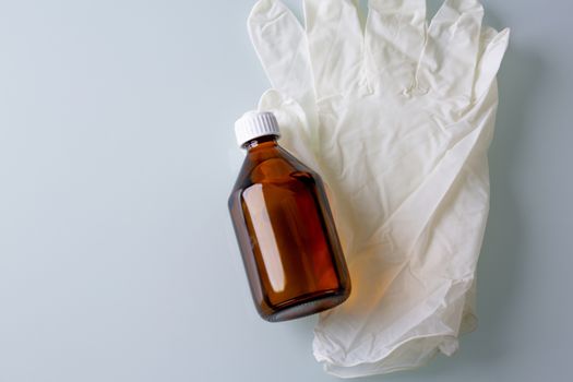 Top view of alcohol solution and rubber gloves on a grey background. Space for text