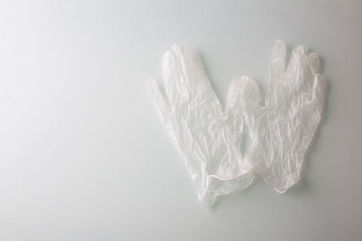 A pair of a transparent latex gloves on a grey background. Space for text