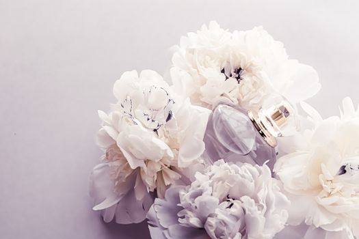 Violet fragrance bottle as luxury perfume product on background of peony flowers, parfum ad and beauty branding design