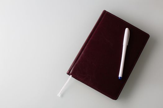 Closeup shot of a pen and a diary in faux leather brown cover. Empty space