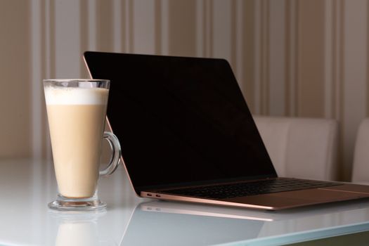 Laptop with a big glass of coffee latte on the table. Study at home concept