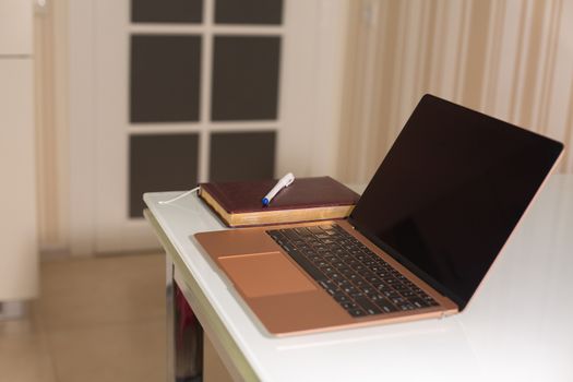 Rose gold laptop with diary and pen on a white glass table. Study at home concept