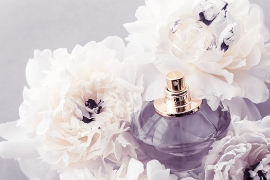 Violet fragrance bottle as luxury perfume product on background of peony flowers, parfum ad and beauty branding design