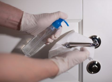 Man using alcohol antibacterial gel and paper napkin to clean door handle