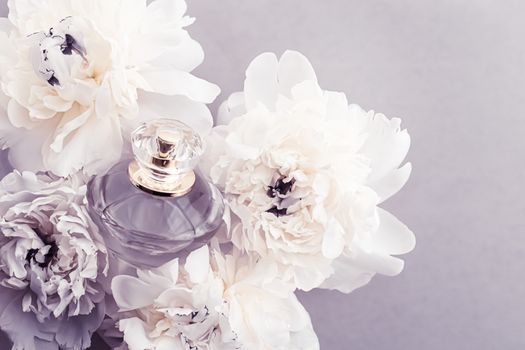 Violet fragrance bottle as luxury perfume product on background of peony flowers, parfum ad and beauty branding design