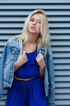 Street photosession of wonderful blonde woman wears casual apparel posing near the metal shutters