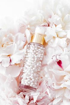 Luxurious cosmetic bottle as antiaging skincare product on background of flowers, blank label packaging for body care branding design