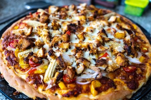 Top view of home made pizza with sauce, vegetables, baby corn, corn, tomatoes, mushrooms and more . Shows the various cooking experiments during the pandemic lockdown