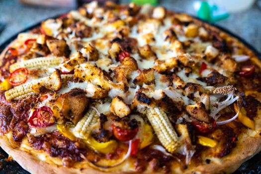 Top view of home made pizza with sauce, vegetables, baby corn, corn, tomatoes, mushrooms and more . Shows the various cooking experiments during the pandemic lockdown