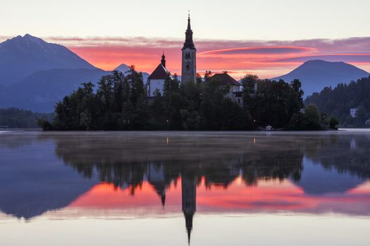 Dramatic sunrise on lake Bled, sunrise view on Bled lake, island, Pilgrimage Church of the Assumption of Maria and Castle with mountain range (Stol, Vrtaca, Begunjscica). Bled, Slovenia,