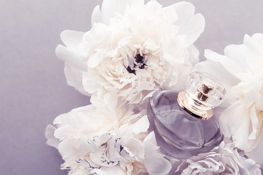 Violet fragrance bottle as luxury perfume product on background of peony flowers, parfum ad and beauty branding design