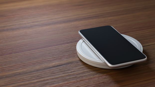 Copyspace of mobile phone charging battery with wireless charger on working table.