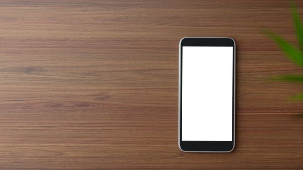 Copyspace of blank screen mockup mobile phone on wooden working table.