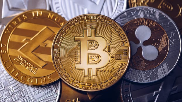 Bitcoin, litecoin and ripple coins currency finance money on graph chart background. Bitcoin as most important cryptocurrency concept. Stack of cryptocurrencies with a golden bitcoin in the middle.