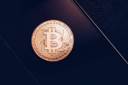 Bitcoin symbol over mobile screen, minimalist approach. Bitcoin on stock market. New digital money. Golden Bitcoin over smartphone display.
