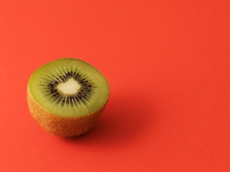 Close-up of a kiwi cut in half. Isolated on a red background. Copy space.