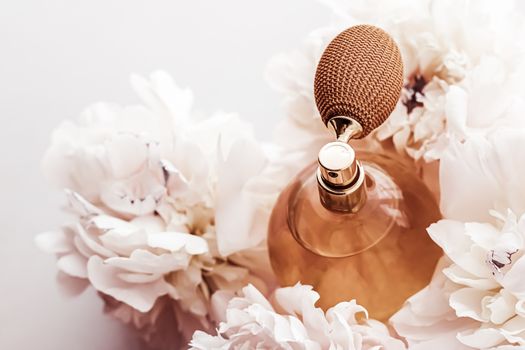 Fragrance bottle as vintage perfume product on background of peony flowers, parfum ad and beauty branding design