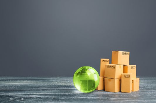 Green glass globe and cardboard boxes. Distribution and trade exchange goods around the world, retail and sales. Global business, import, export. Economic relations commerce. Freight transportation