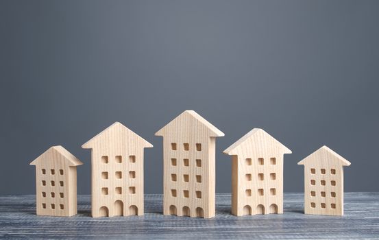 Row of wooden figures of residential buildings. Affordable comfortable housing. Search purchase best option apartment and real estate, rent and sale. Mortgage. Cozy ecological modern neighborhood.
