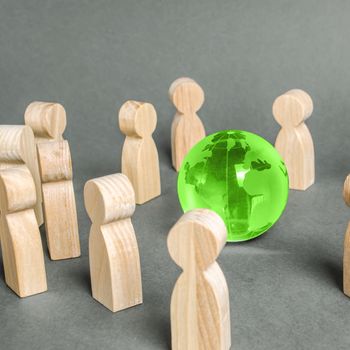 People surrounded a green Globe world planet earth. Cooperation and collaboration of people around the world. Outsourcing and joint work on projects. Diplomacy. crowdfunding. Preserving environment