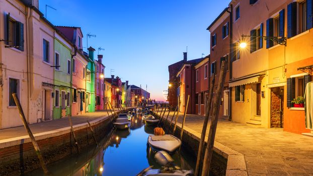 Street view with colorful buildings in Burano island at night, Venice, Italy. Architecture and landmarks of Burano, Venice postcard. Scenic canal and colorful architecture in Burano island near Venice, Italy