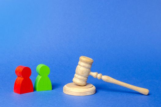 Two figures of people opponents stand near the judge's gavel. The judicial system. Court case, settling disputes. Legal advice, lawyer services. Conflict resolution in court, claimant and respondent.