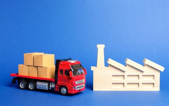 A red truck loaded with boxes stands near the factory. Services transportation of goods products, logistics in the industry, economic relations, infrastructure. Transportation company. Warehousing