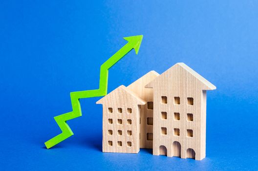 figures of residential buildings and green arrow up. Rising value and price. Apartments for sale. Growth in demand and liquidity for real estate, increase in rates for the maintenance of buildings.