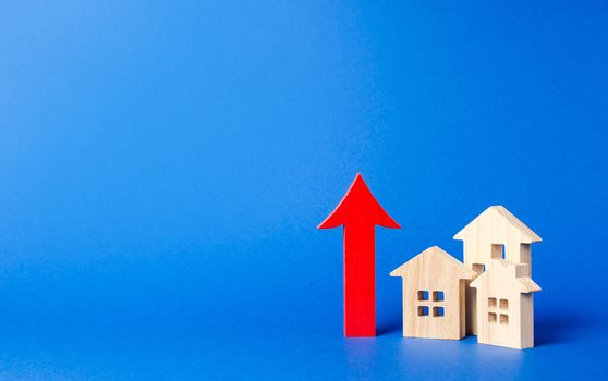 three wooden houses and red up arrow. High rates of construction, high liquidity. Supply and demand. prices for housing, building maintenance. limit on high-rise buildings. Real estate value increase.