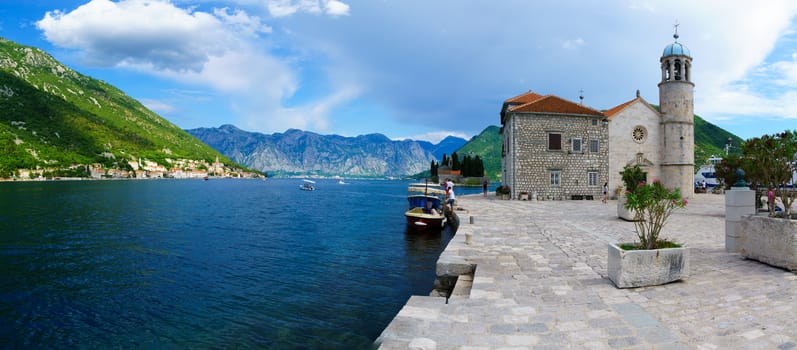 PERAST, MONTENEGRO - JUNE 28, 2015: Panoramic view of Our Lady of the Rocks church, and the town of Perast, with local and tourists. The Bay of Kotor, Montenegro