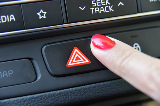 Female finger hitting car emergency light botton